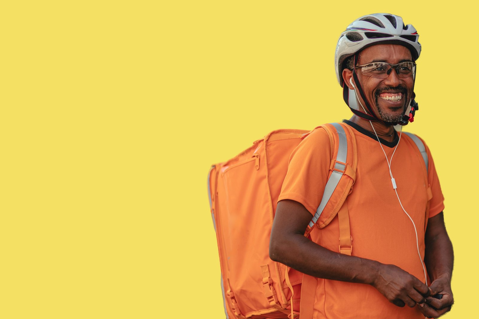 Un livreur souriant, sac de livraison sur le dos, sur fond jaune